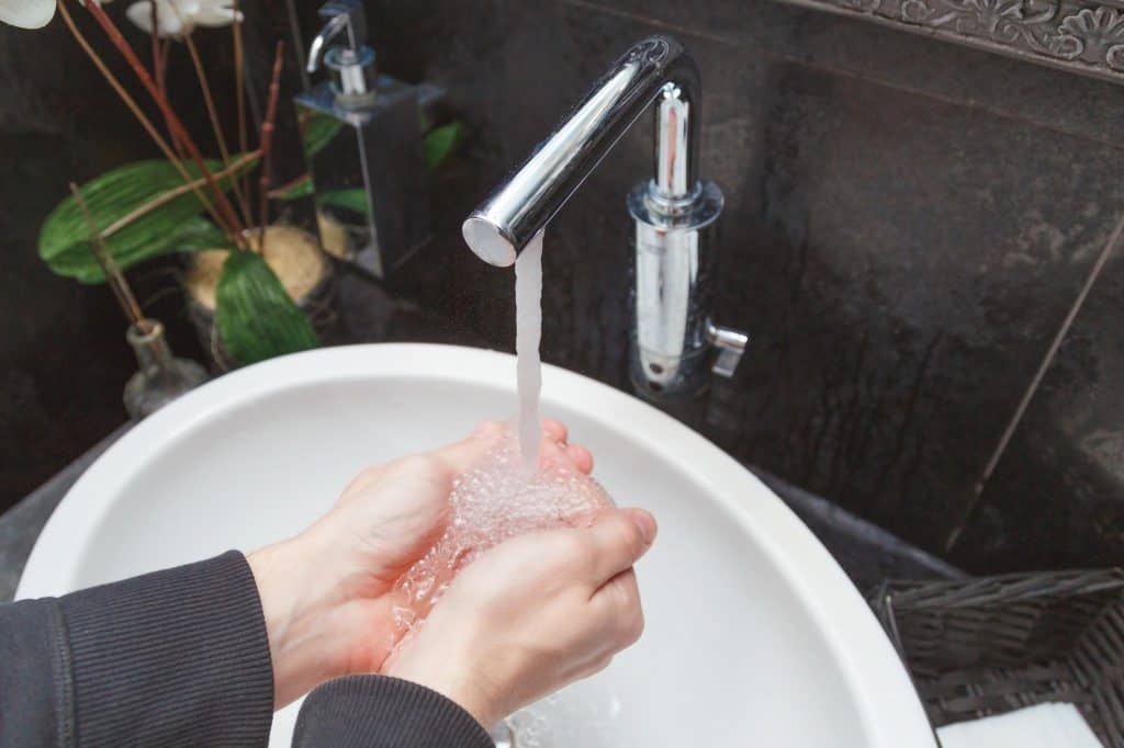 Washing of hands under the crane with water